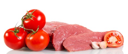 A piece of raw beef, tomatoes and garlic isolated on white background.の写真素材