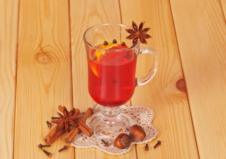 Mulled wine with orange, cloves, anise and cinnamon on a background of light wood.の写真素材