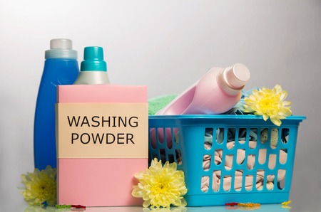 Detergents, liquid powder, bleach and soiled laundry in a basket on a light gray background.の写真素材