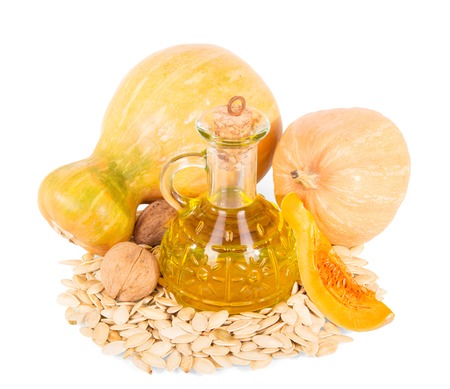Fresh ripe pumpkin seeds, walnuts and oil decanter isolated on white background.の写真素材