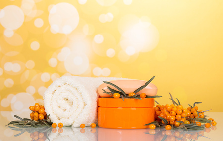 Sea buckthorn soap, jar of cream and towel on abstract yellow background.の写真素材