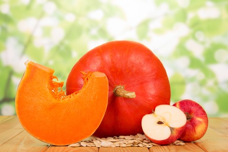 Ripe pumpkin seeds and apples on abstract green background.の写真素材