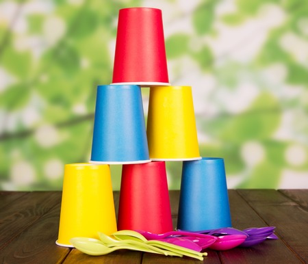 Bright disposable cups and plastic spoons on an abstract green background.の写真素材