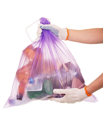 Full garbage bag in female hands isolated on white background.の写真素材