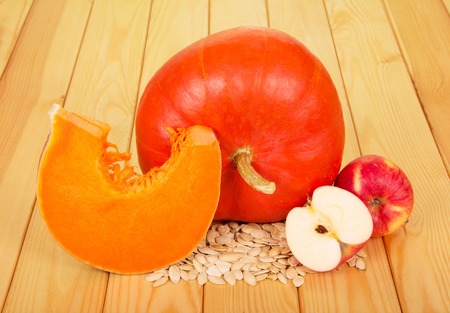 Pumpkin seeds and apples on a background of light wood.の写真素材