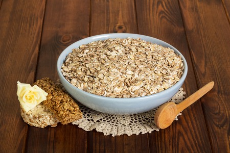 A bowl of oatmeal, bar, rose and spoon on dark wooden background.の写真素材