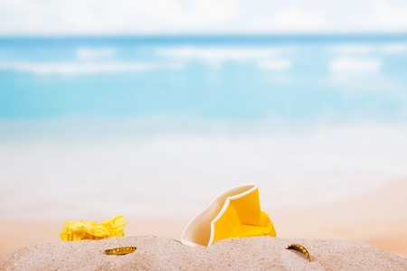 Household and food waste in the sand on the beach, background.