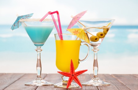 Two cocktails, a glass of juice and starfish on a sea background.の写真素材