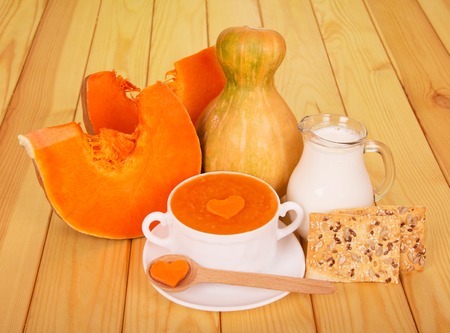 A cup of pumpkin puree, a jug of milk and cookies on light wood background.の写真素材