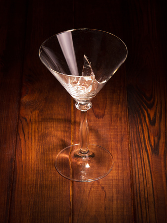 Broken glass of martini on a dark wood background.の写真素材