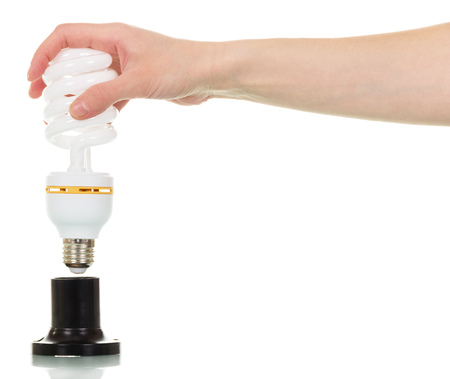 Energy saving fluorescent light bulb in a female hand isolated on white background.の写真素材