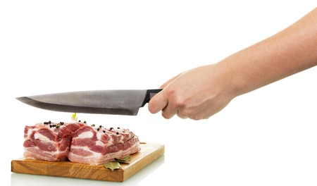 Raw pork with spices on a cutting board, a hand holding a knife isolated on white background.の写真素材