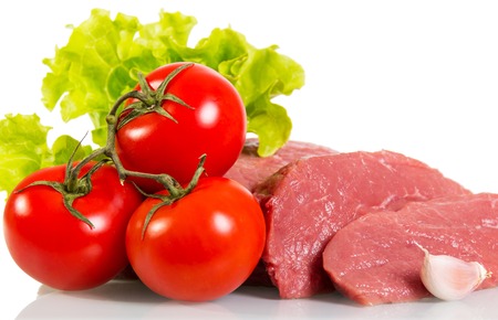 Pieces of fresh raw meat, tomatoes and lettuce isolated on white background.の写真素材