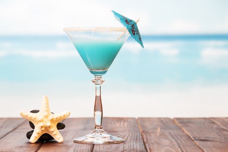 Cocktail with umbrella and starfish on a sea background.の写真素材