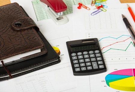 Notebooks, calculator and various stationery items on the desktop background.の写真素材
