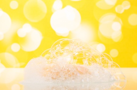 Soap with foam in the bathroom on an abstract yellow background.の写真素材