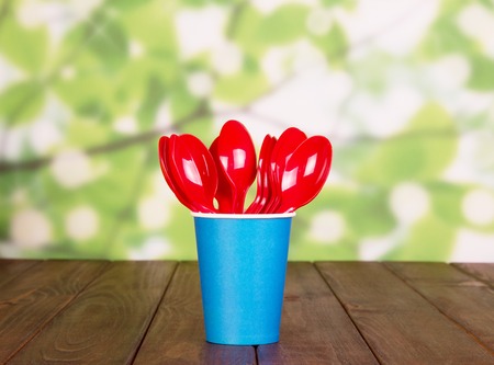 Disposable cups and plastic spoons on an abstract green background.の写真素材