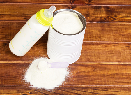 Bank of milk powder and baby bottle with the mixture in a dark Dere.の写真素材