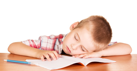 Boy asleep at his desk on a notebook isolated on white background.の写真素材