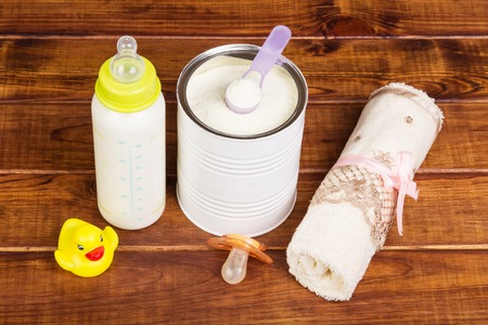 Baby milk formula feeding bottle, pacifier and towel on a background of dark wood.の写真素材