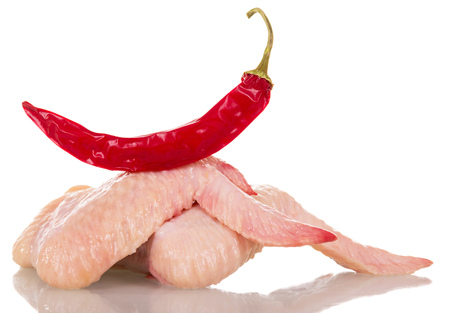Raw chicken wings and red hot peppers isolated on white background.の写真素材