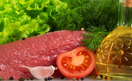 Raw beef with herbs, spices and vegetable oil background.の写真素材