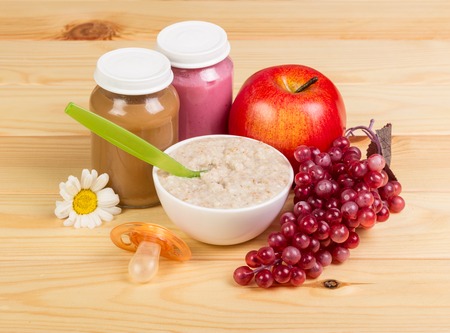 Food for children: mashed potatoes, a bowl of oatmeal and fruits on a background of light wood.の写真素材