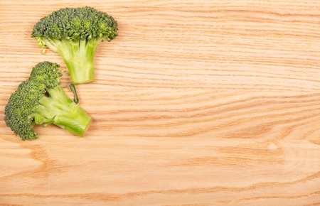 The cut pieces of fresh broccoli on a background of light wood.の写真素材