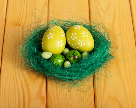 Are different Easter eggs in a nest on a background of light wood.の写真素材