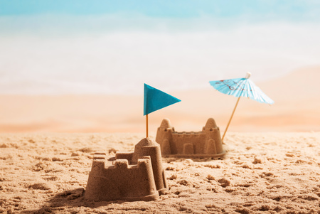 Sandcastles with a flag and an umbrella on the beach.の写真素材