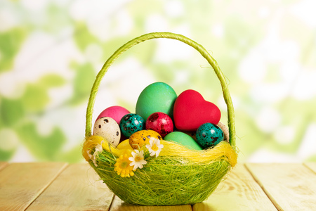 The various Easter eggs in a basket and red heart on an abstract green background.の写真素材
