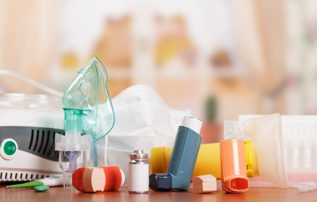 Compressor and ultrasonic nebulizers, aerochamber, inhaler, thermometer and medicines to treat asthma on abstract pink background.の写真素材
