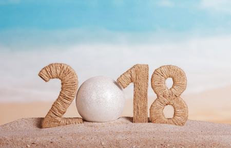New Year inscription and 2018 instead of the number 0 - the white ball on the sand.の写真素材