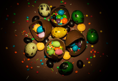 Easter eggs, chocolate eggs are the broken, various dragees and decorations for Easter on a brown background.の写真素材