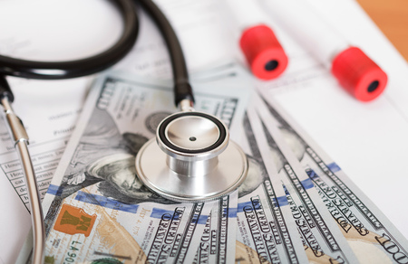 Medical stethoscope, vacuum tubes for blood sampling, dollars and a sheet of paper with test results on the background of the table.の写真素材
