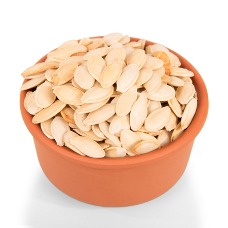 A bowl filled with pumpkin seeds is isolated on a white background.の写真素材