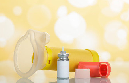 Inhaler, aerochamber and medicine on abstract yellow background.の写真素材