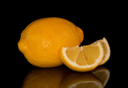Whole lemon and chopped slices isolated on black backgroundの写真素材
