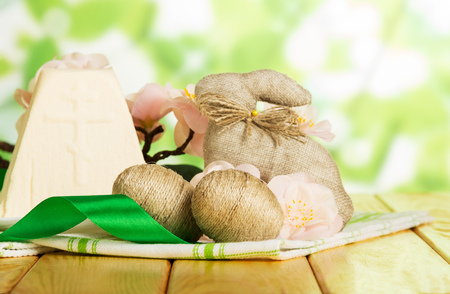 Traditional Easter cheese dessert, easter bunny, eggs entwined with twine, cloth and ribbon on abstract green background.の写真素材