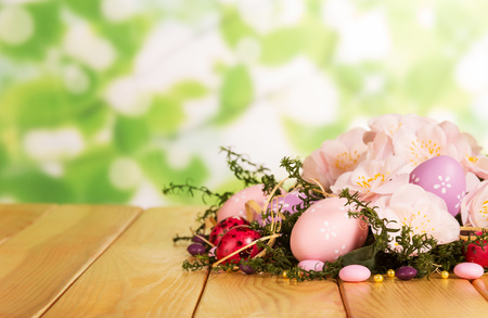 Colored Easter eggs, candy, grass, branch with flowers and ribbon on abstract green background.の写真素材