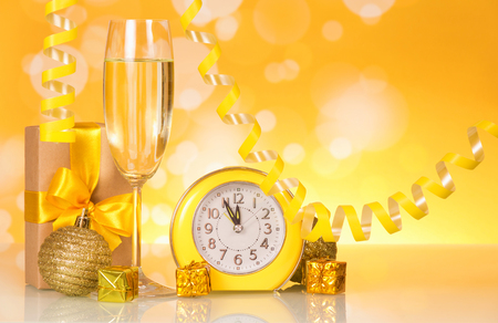 Wine glass with champagne, presents and watches on bright sparkling backgroundの写真素材