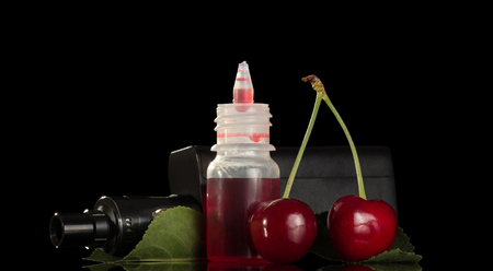 Electronic cigarette with cherry liquid for vaping isolated on black backgroundの写真素材