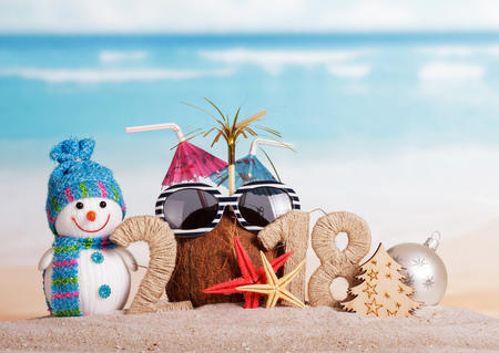 New Year inscription 2018, coconut with straws instead of the number 0 and sunglasses, snowman, Christmas tree, Christmas ball and starfish on the sand.の写真素材