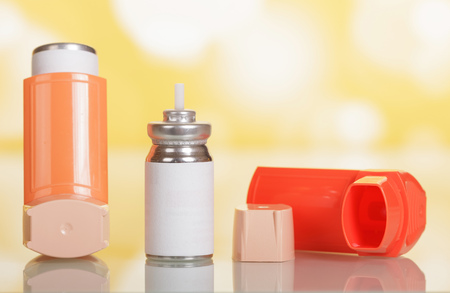 Device for inhalation with a dispenser and capsule with medicine on yellowの写真素材