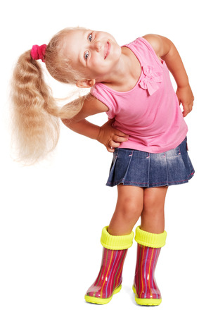 An impish little blond girl in a blouse, a skirt and rubber boots isolated on white background.の写真素材