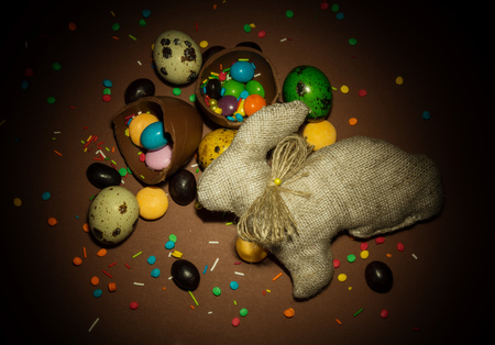 Easter bunny, Easter eggs, chocolate eggs are the broken, various dragees and decorations for Easter on a brown background.の写真素材