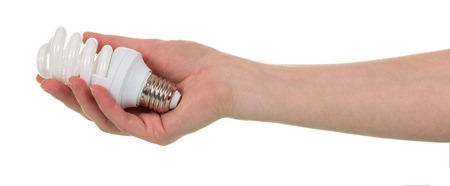In a female hand a fluorescent light bulb is isolated on a white background.の写真素材