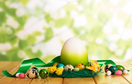 Colorful Easter eggs in the nest and the next, candy, one large, abstract ribbon on a green background.の写真素材
