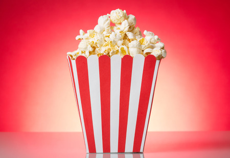 Full container with popcorn isolated on a red backgroundの写真素材