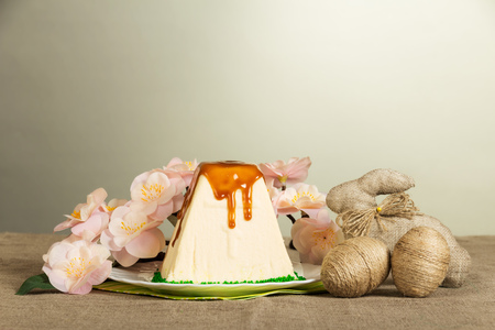 Traditional Easter curds dessert watered glaze, easter eggs entwined twine, easter bunny and branch with flowers on a gray background.の写真素材
